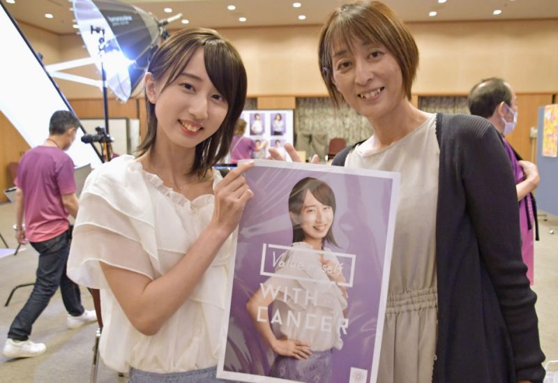 Miho mỉm cười với mẹ khi cầm bức ảnh chụp tại sự kiện.