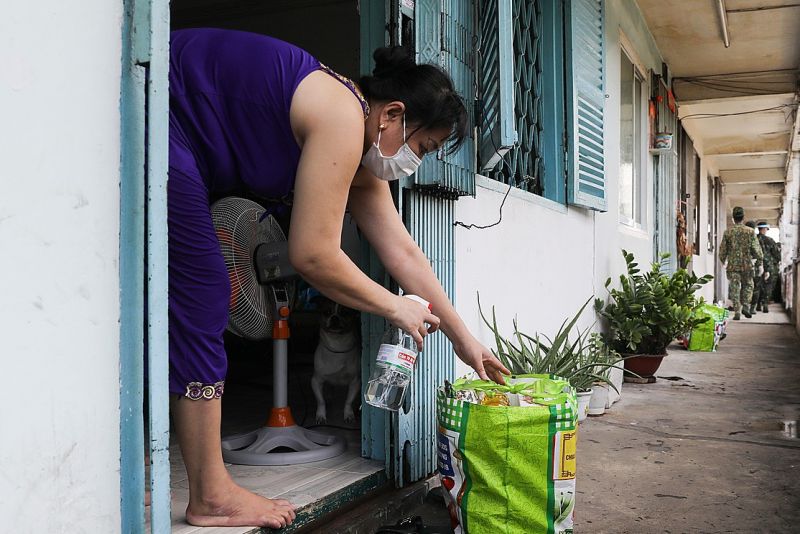 接触を避けるため兵士が去ってから荷物に消毒液をかけ受け取る住人　ⓒ Vn Express