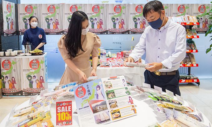 ホーチミン市1区の日本製品専門モールで、お客さんに日本の即席めんを紹介するホクセイシャベトナムの社長（右）　ⓒ VnExpress