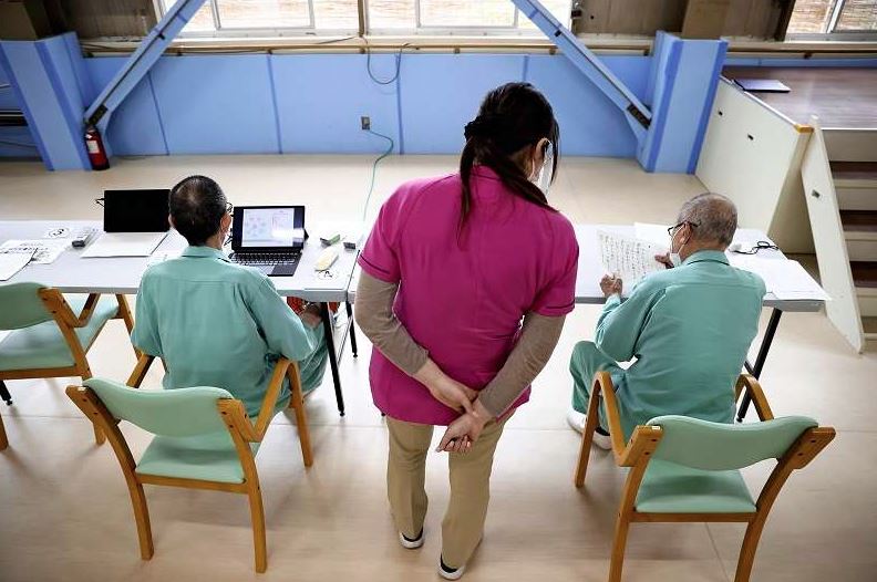 Một nhân viên chăm sóc đang hỗ trợ các tù nhân lớn tuổi cải thiện chức năng thể chất