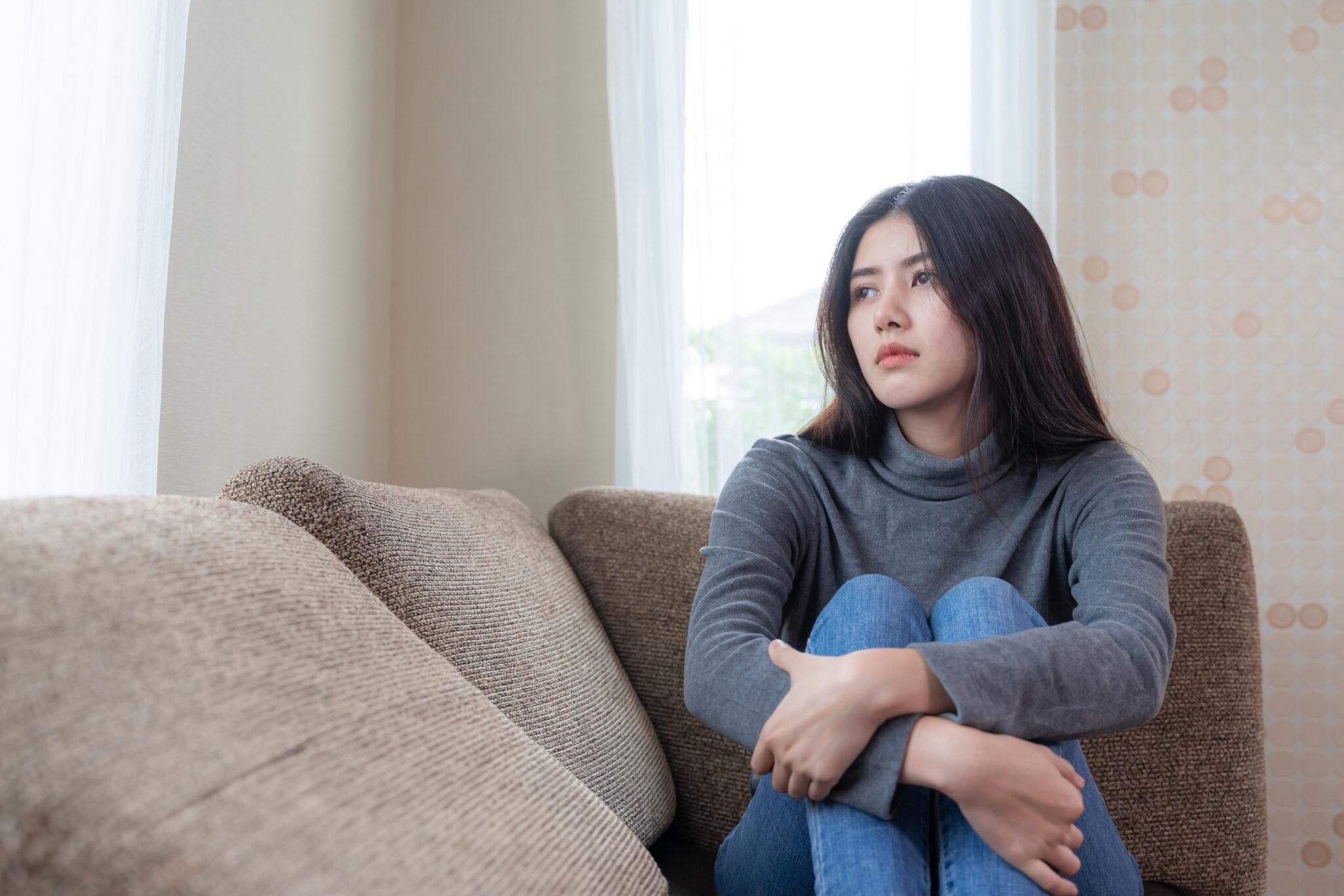 unhappy-asian-pretty-young-woman-siting-alone-couch-with-feeling-sadness-scaled